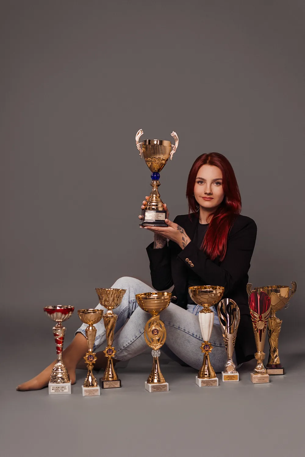 Kätlin Liaks holding a trophy, surrounded by her competition trophies